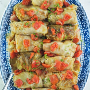 cabbage rolls on blue and white platter with serving spoon