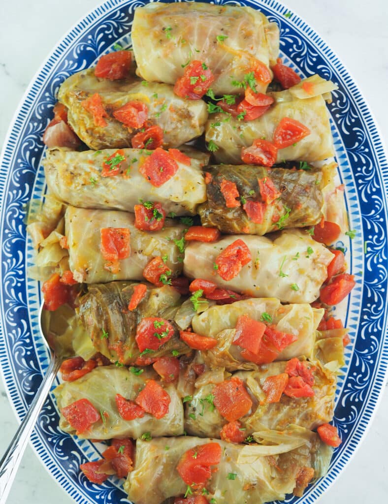 cabbage rolls on blue and white platter with serving spoon