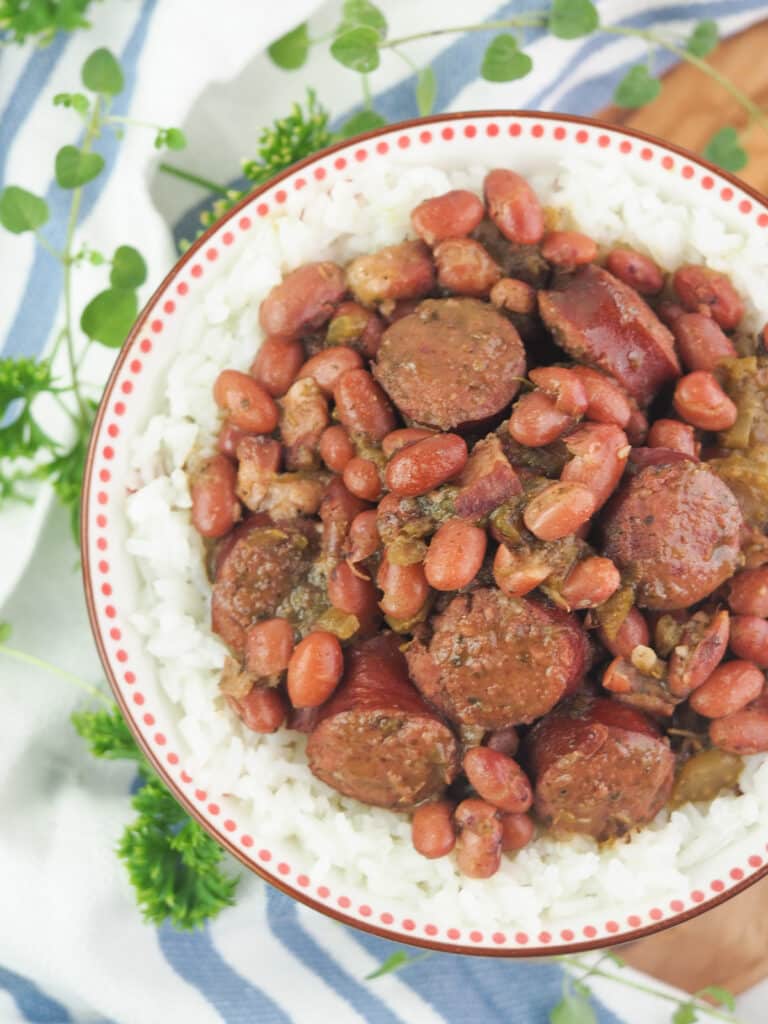 vertical red beans and rice with sausage next to blue and white linen towel