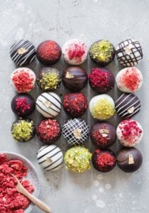 Decorated truffles arranged in rows and columns on a table top.