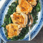 chicken thighs on blue platter with spinach