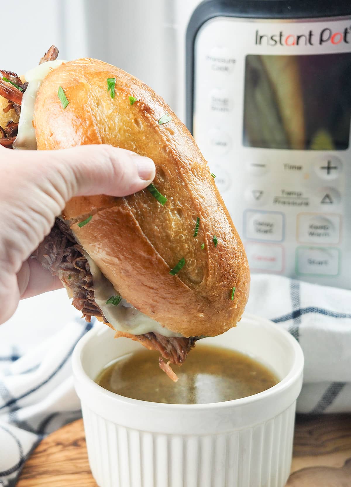 sandwich being dipped in au jus gravy