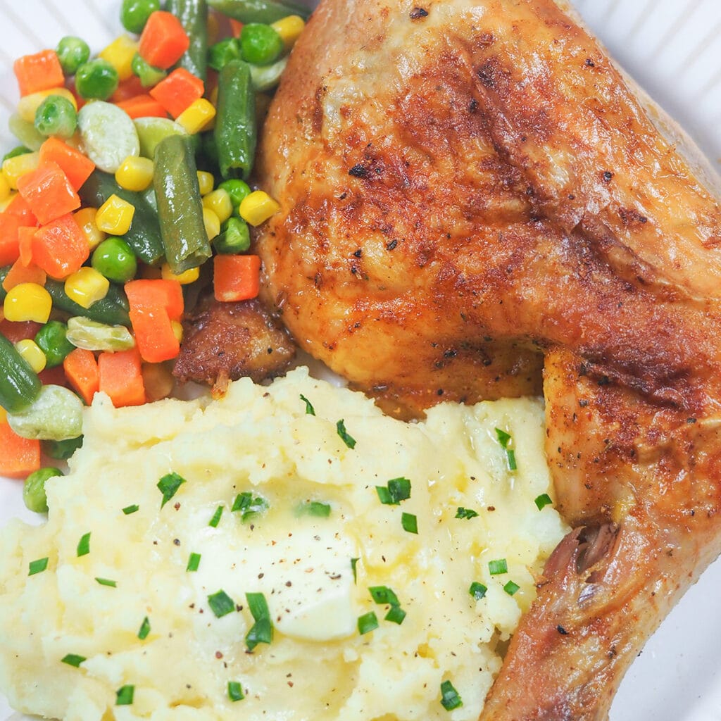 chicken on plate with potatoes and mixed vegetables