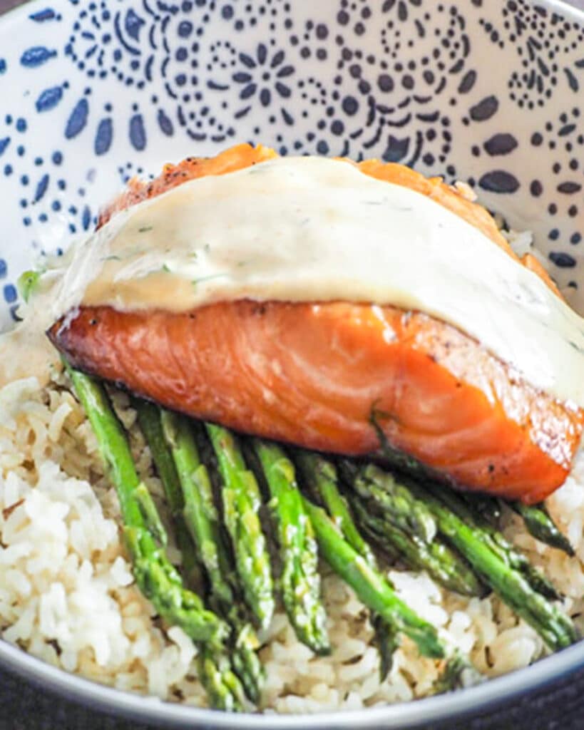 salmon with sauce on bed of rice with asparagus